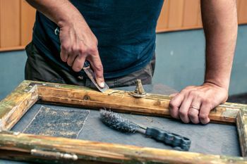 Schilder herstelt houtrot in een houten raamkozijn
