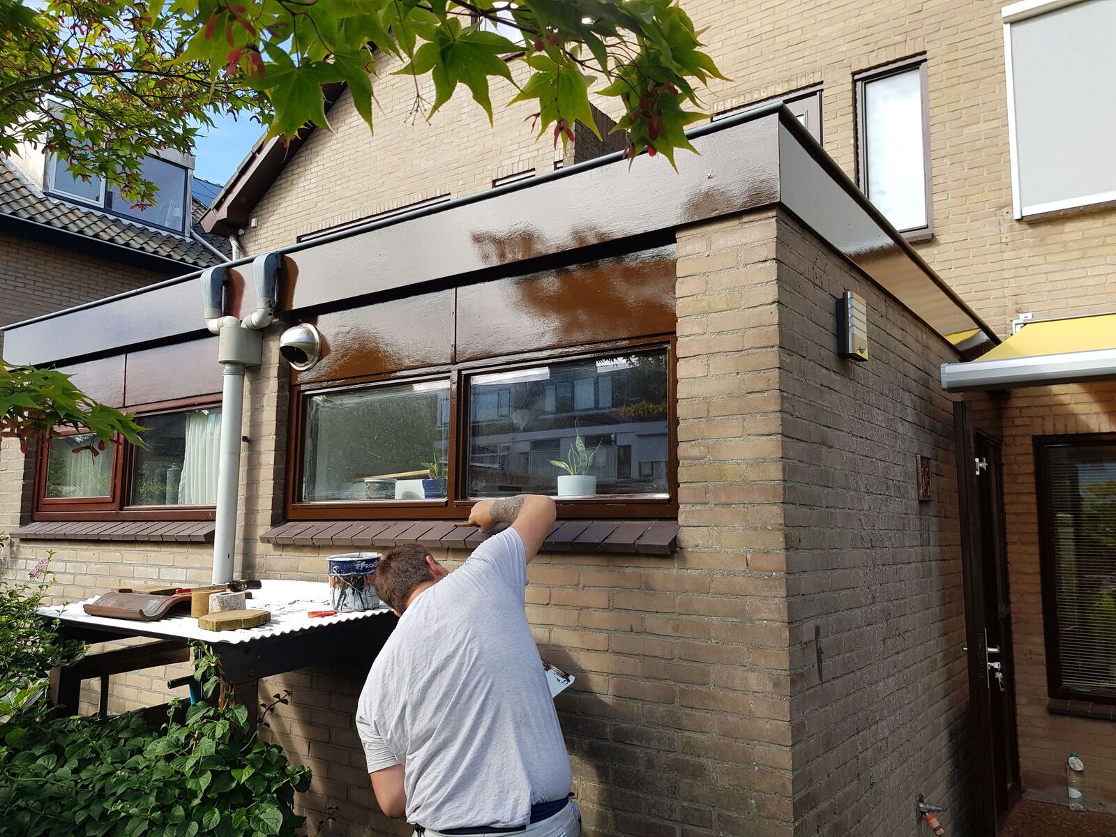 Schilder aan het werk aan een gevel en kozijnen